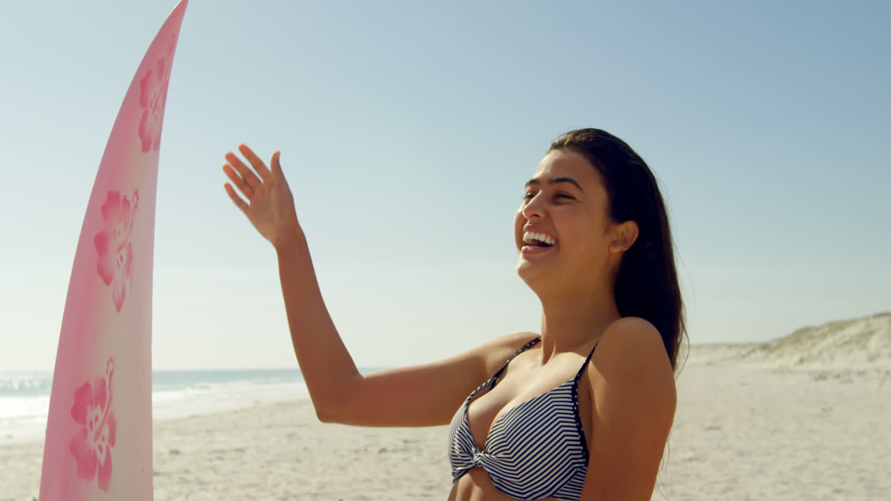 여성 서퍼가 해변에서 머리를 뒤집고 있습니다.