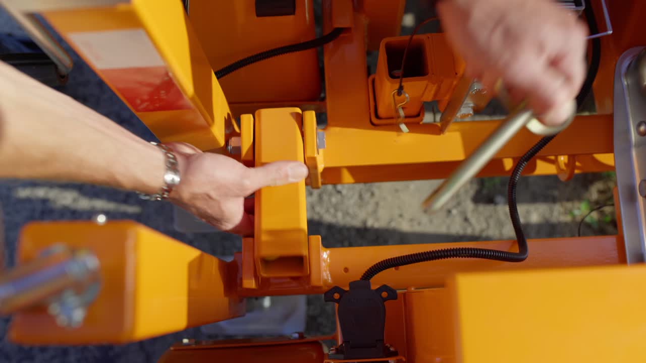 las manos de un trabajador entran en el marco para quitar un alfiler de bloqueo del brazo pequeño y naranja en una luz de parada móvil