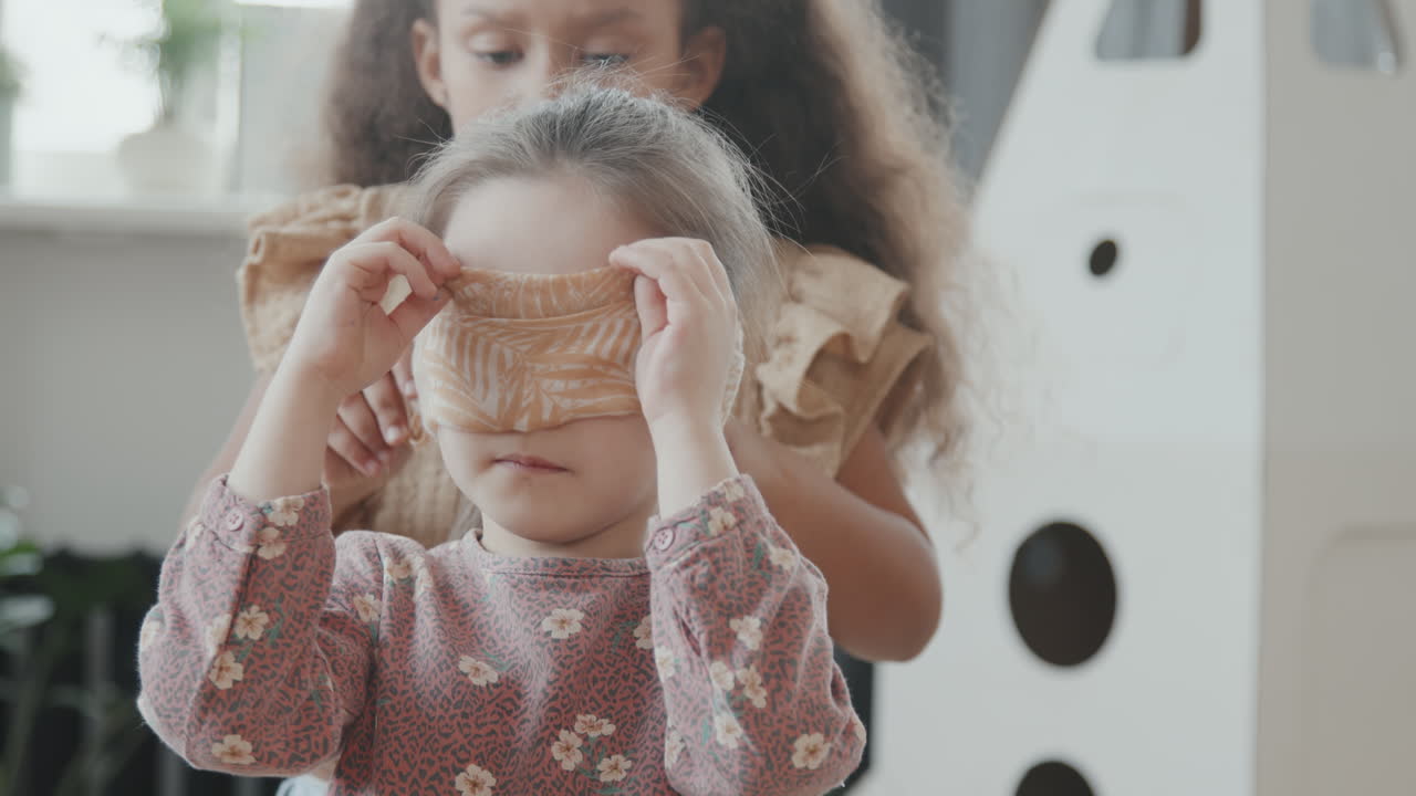 Little Girl Putting Blindfold on Her Friend
