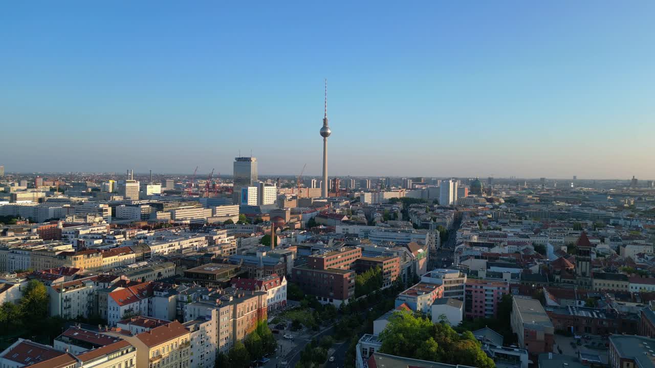 la torre de televisión de berlin de pie alto sobre la torre y el ayuntamiento rojo, bañado en el cálido resplandor de la hora de oro. fabulosa vista aérea vuelo descendiendo drone