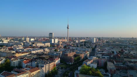 berlin tv tower standing tall over the tower and red town hall, bathed in the warm glow of golden hour. fabulous aerial view flight descending drone