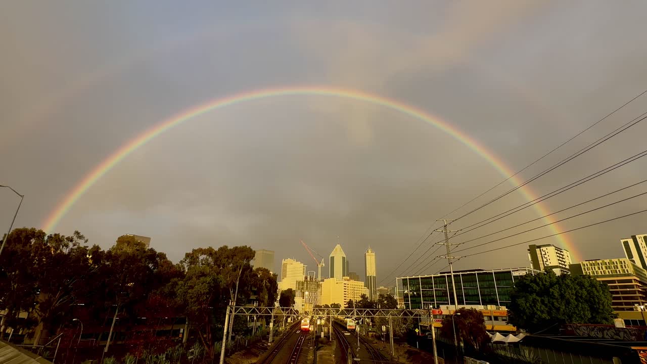 arco iris sobre perth cbd, australia occidental y las vías del tren en el día del cielo gris