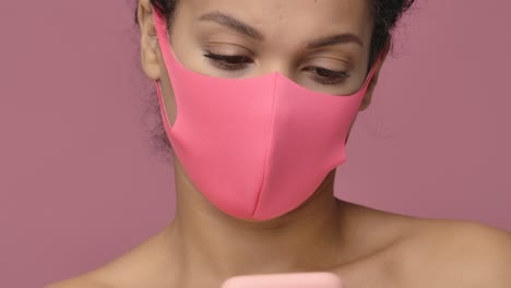 woman with pink face mask using smartphone