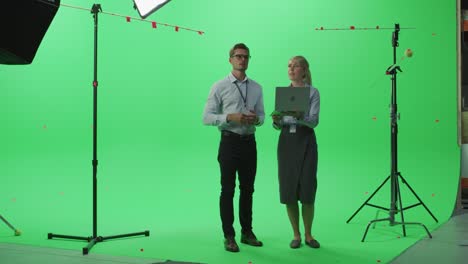 female and male colleagues wearing casual clothes talking, using laptop computer in green screen mock up chroma key studio. business, corporate office, work, technology concept.