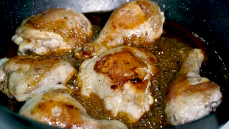 delicious chicken pieces cook in pan of bubbling sauce, slow motion closeup