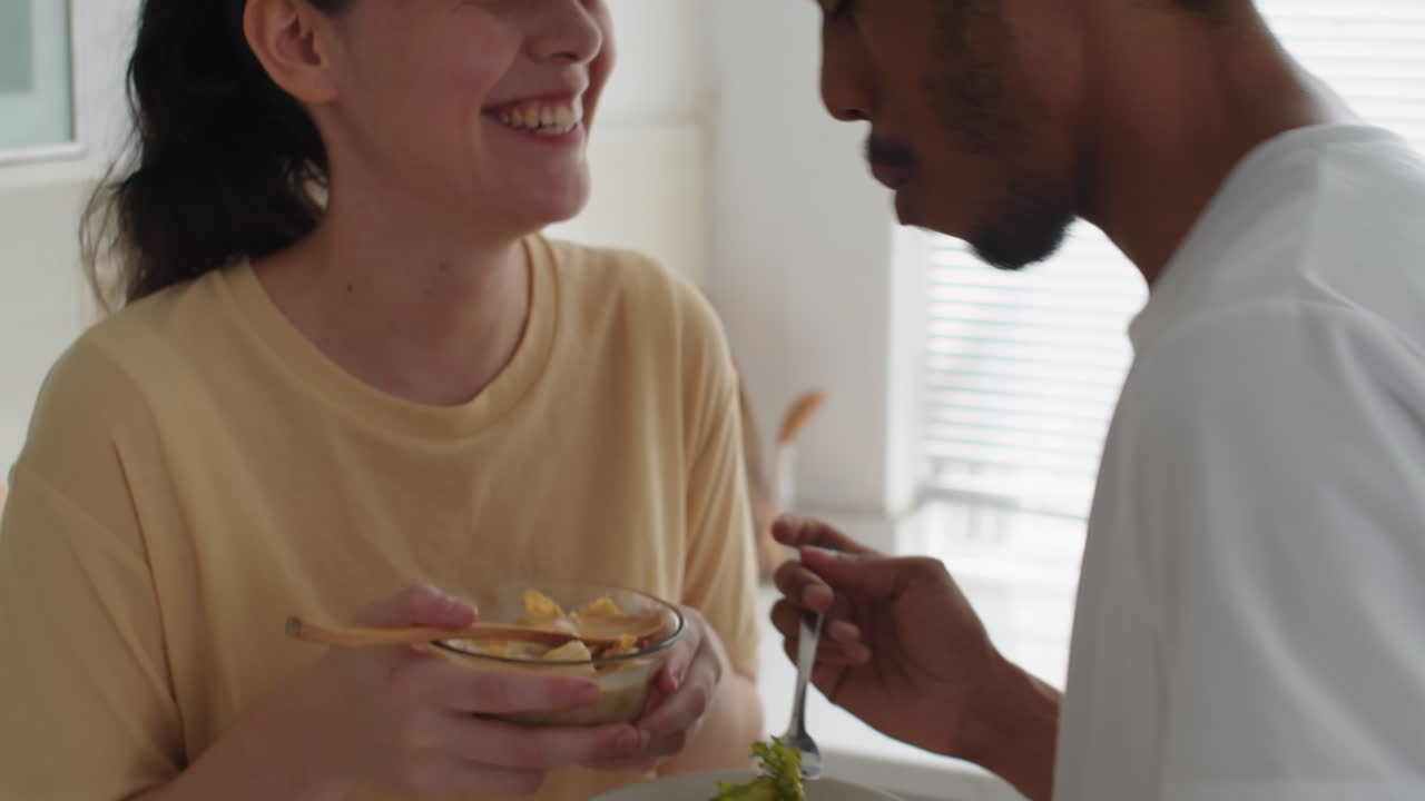 Husband Feeding Wife with Green Salad during Home Breakfast