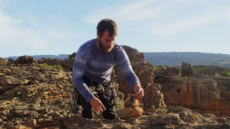 climber stacks the stone at top of cliff 4k