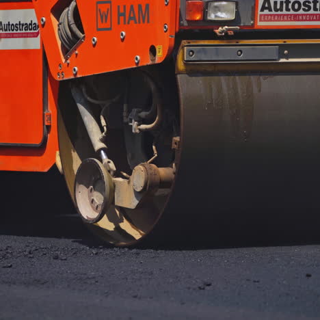 Road roller paving the asphalt road. Asphalt roller rolls fresh asphalt. Reconstruction on the highway. Close-up.