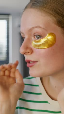 mujer aplicando parches de oro en los ojos