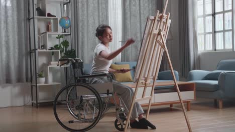 mujer en silla de ruedas pintando en la sala de estar