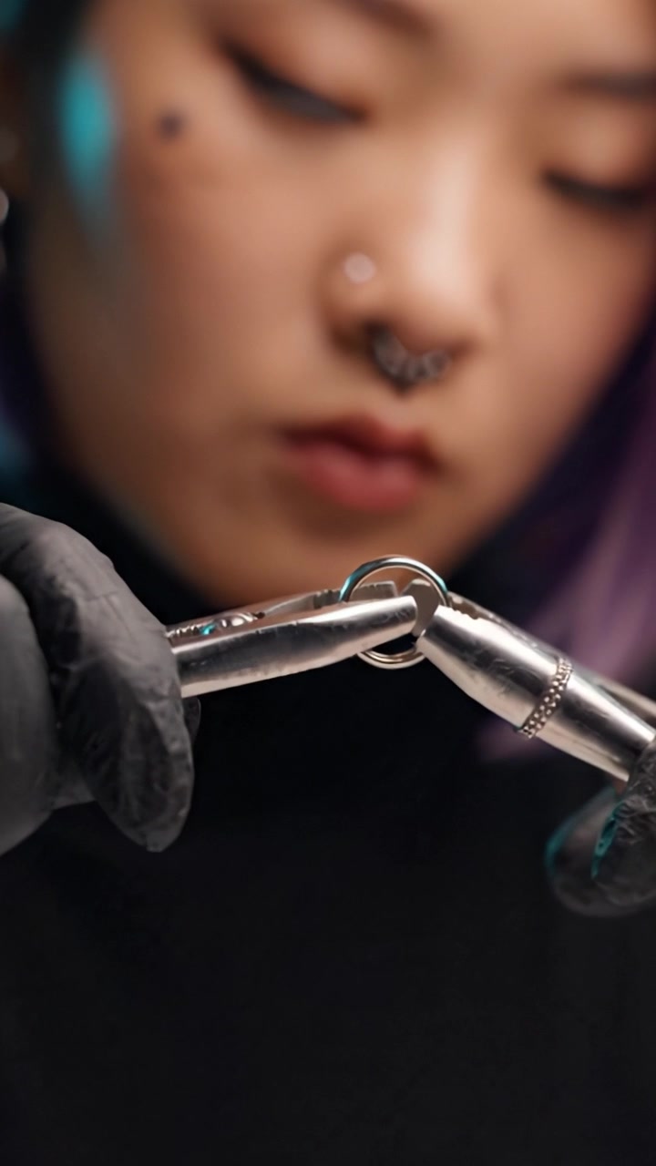 Primo piano dettagliato di un abile artigiano che usa le pinze per manipolare un piccolo anello in un coinvolgente processo di creazione di gioielli