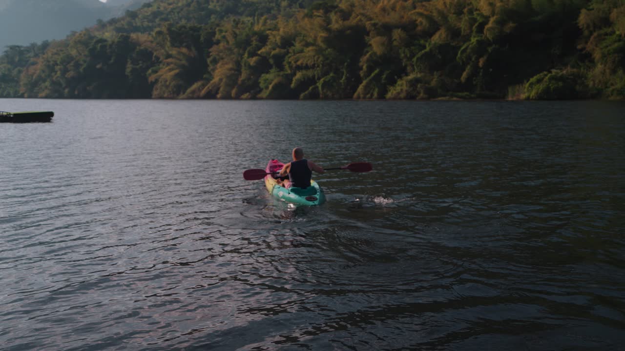 Uomo in kayak su un lago sereno circondato da montagne verdi