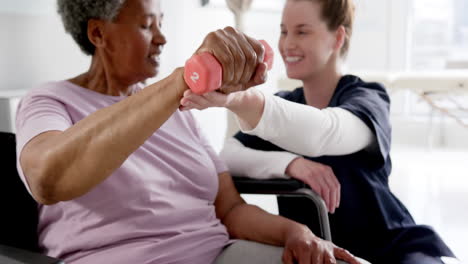 diverse senior woman exercising with weight and female doctor advising in hospital, slow motion