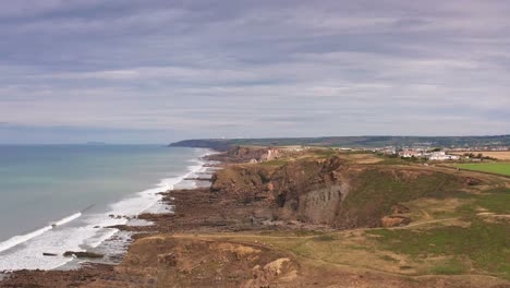 aerial drone flyover beach and sea cliff in widemouth bay north cornwall