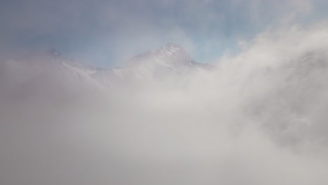 Drone-video-flying-through-the-clouds-towards-a-snowy-mountain-range