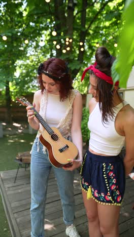 two girls playing ukulele outdoors