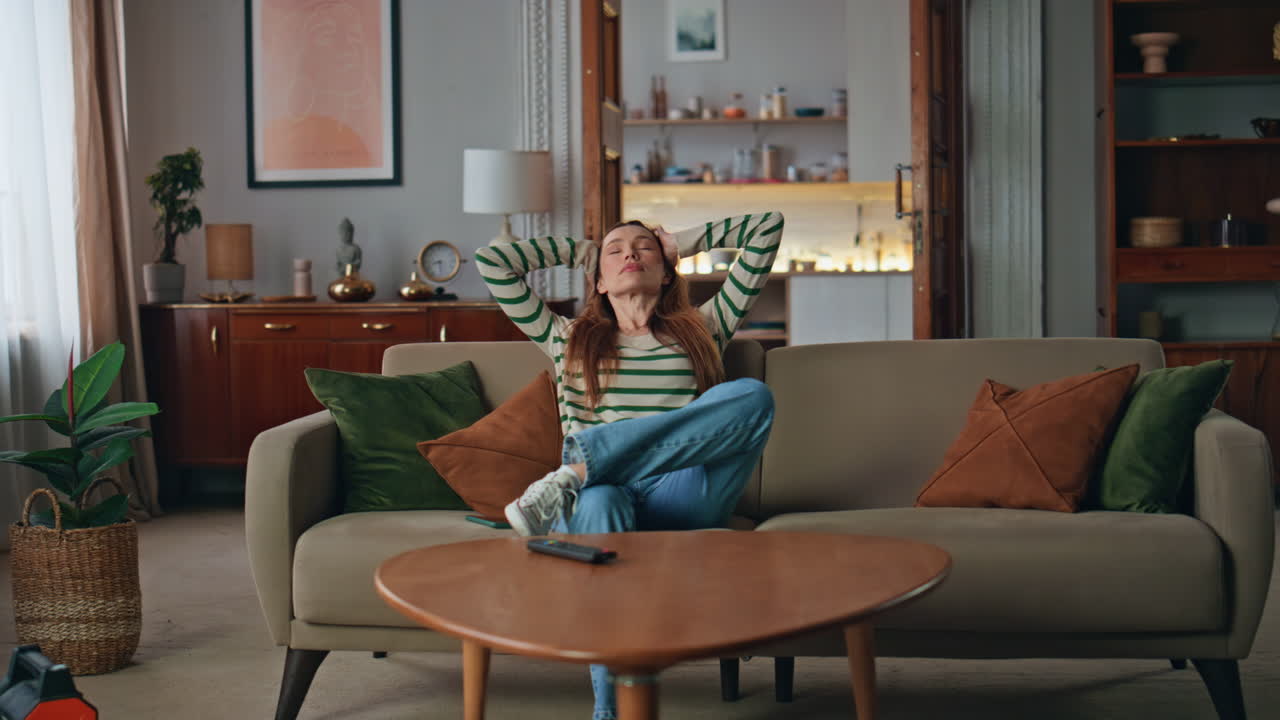 müdige dame sitzt auf der couch und entspannt sich nach einem harten tag zu hause. frau nimmt das handy.