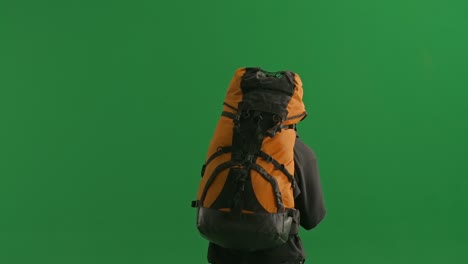 person with a large orange backpack on a green screen