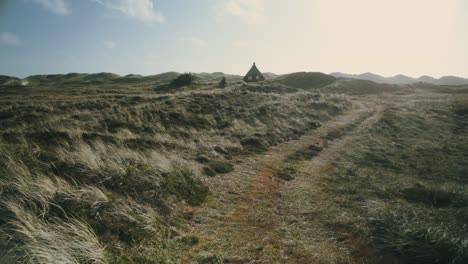 path towards single red house in nature reserve, walking pov