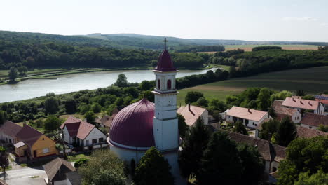 Vista-Aérea-De-La-Antigua-Iglesia-Cerca-Del-Estanque-De-Pesca-En-El-Pueblo-De-Palkonya-En-El-Condado-De-Baranya,-Hungría