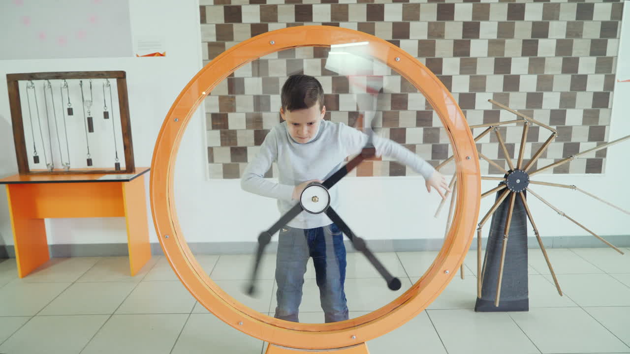 Child looks at the perpetual motion machine in the children's scientific museum. Concept of physics