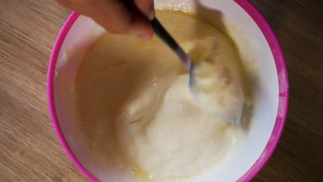 female hands mixing batter for american pancakes in close up homemade shot while camera is moving around.