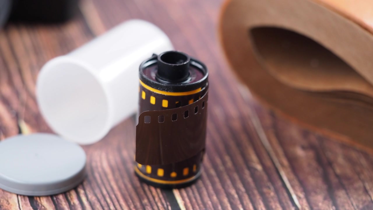 Gulungan Film 35mm dan Tabung Plastik di atas Meja Kayu