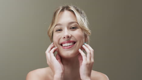 Portrait-of-smiling-caucasian-woman-with-hair-up-touching-her-face,-copy-space,-slow-motion