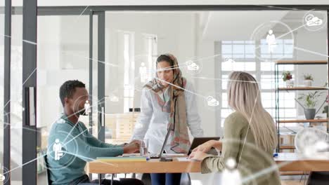 Animation-of-network-of-digital-icons-against-diverse-colleagues-discussing-together-at-office