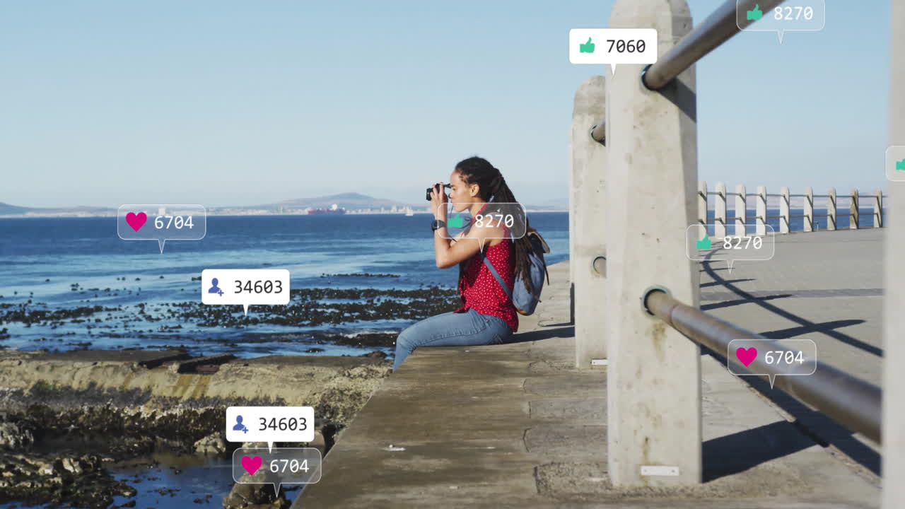 Social media engagement animation over woman photographing ocean from pier