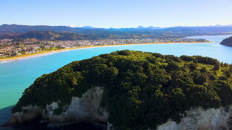 aerial view of lush green hauturu island in new zealand with whangamata beach in background at summer