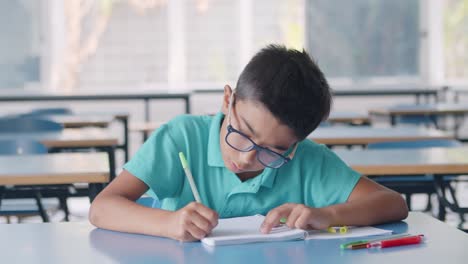 Focused-Latin-pupil-boy-wearing-glasses-writing-on-paper