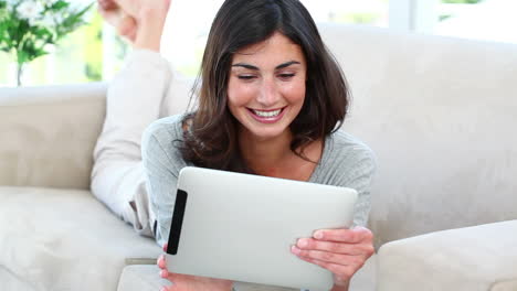 chica usando su tableta mientras está acostada