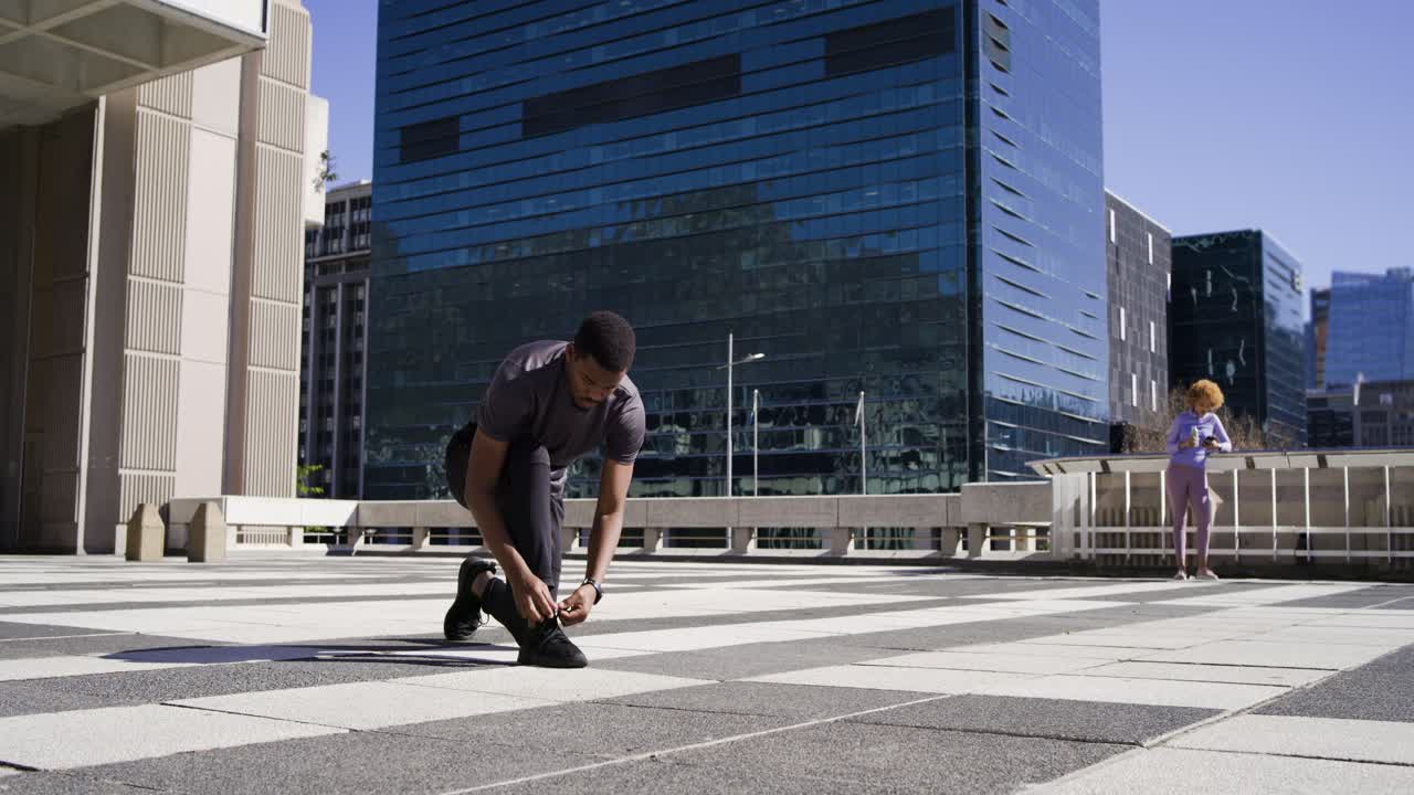 Adult African American man tying shoe on rooftop plaza, noticing lace to resume jogging, copy space
