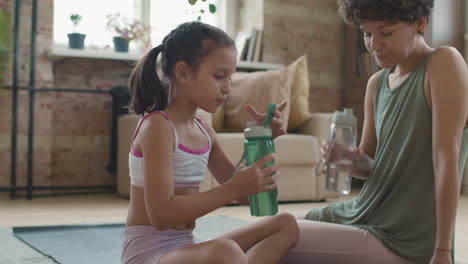 madre e hija bebiendo agua después del ejercicio