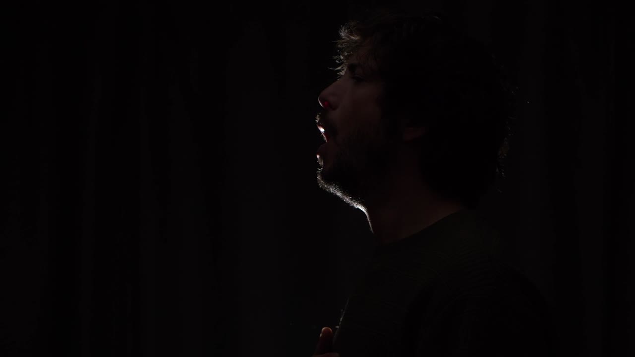 A sick man coughing with a dark background