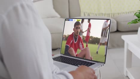 Video-Einer-Person,-Die-Auf-Der-Couch-Sitzt-Und-Sich-Ein-Fußballspiel-Auf-Dem-Laptop-Ansieht