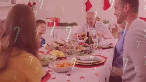 animación de bastones de caramelo cayendo sobre una familia caucásica sonriente cenando