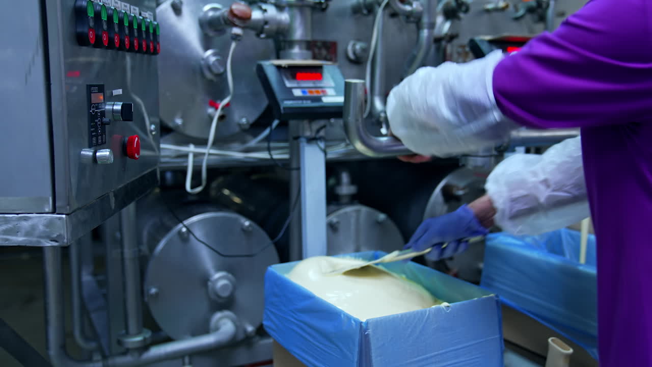 Liquid butter is pouring from the pipe into the container. Factory for the production of butter. Automated line. Food production