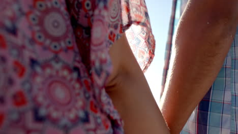 primer plano de una pareja caucásica tomándose de la mano en la playa