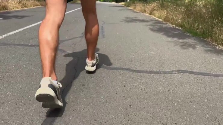 Uomo che fa jogging su strada asfaltata in estate.