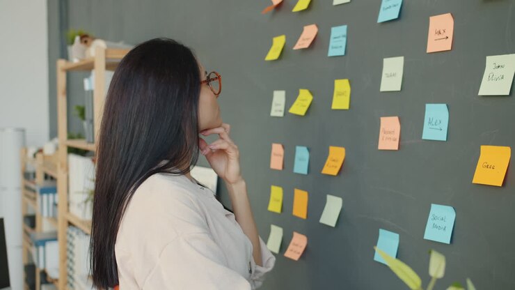Woman Planning Strategy on a Wall with Post-it Notes