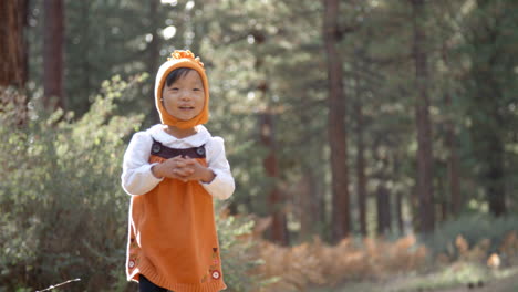 asian toddler girl walking alone in a forest, front view