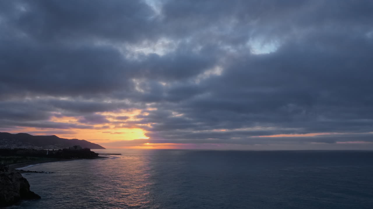 Experience magic of a golden hour time-lapse capturing serene sunrise over a calm sea near a beautiful rocky coastline