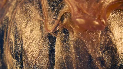 golden ink particles flows in water as colorful chaos on the black background