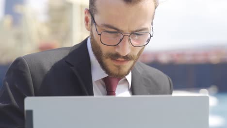 Businessman-working-on-laptop-by-the-sea-in-the-city.