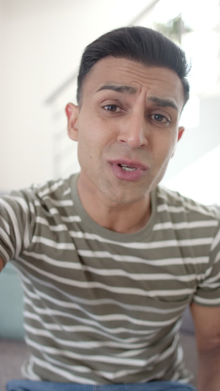 Vertical video of happy emotional biracial man having video call and kissing envelope, slow motion