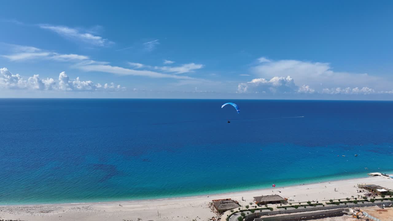 Paraglider above turquoise sea at Palase Green Coast on a bright and peaceful day