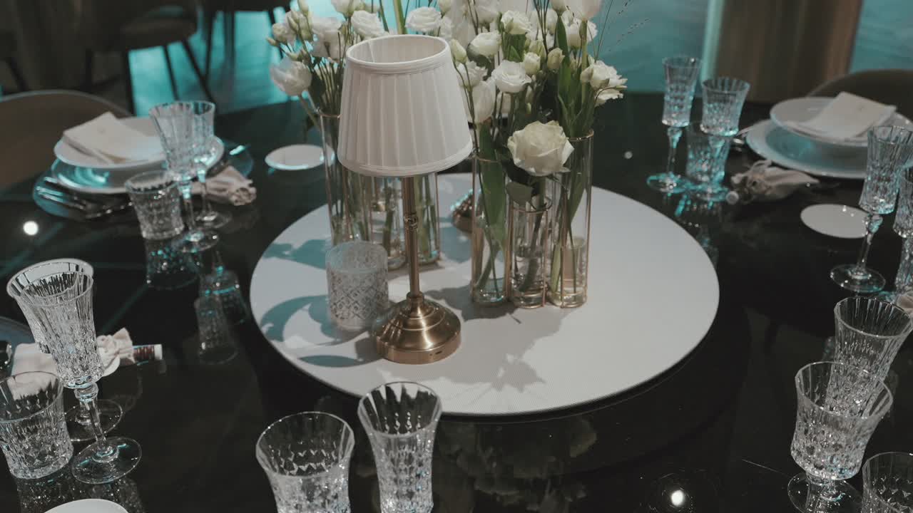 Crystal glassware and white florals on a modern black table centerpiece at wedding reception