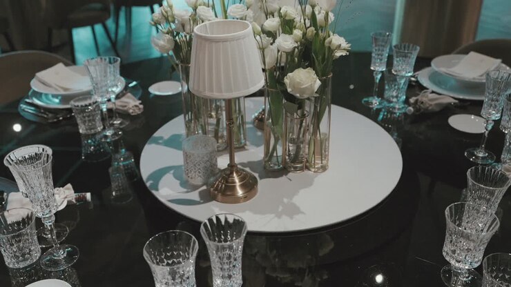 Crystal glassware and white florals on a modern black table centerpiece at wedding reception